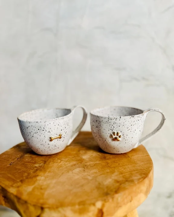 Filiżanka ceramiczna 300 ml stracciatella ze złotą łapką i złotą kostką stojąca na stole