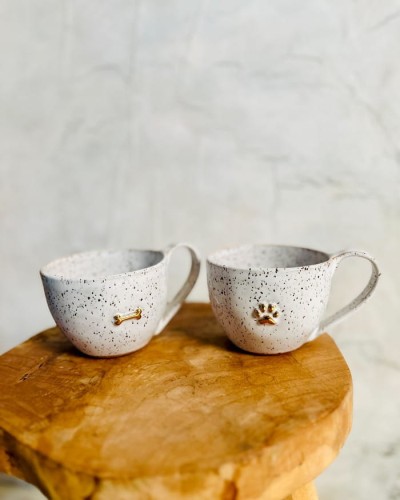 Kubek ceramiczny 400 ml stracciatella ze złotą łapką i złotą kostką stojący na stole